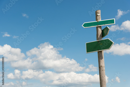 Green signpost with blue sky and white clouds in background