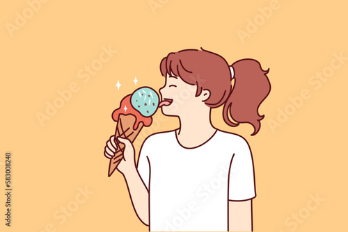 School-age girl licks large ice cream in waffle cone with fruit or caramel icing. Happy teenage girl eating ice cream enjoying summer dessert that helps to escape heat and refresh 
