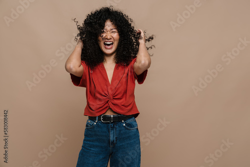 Cheerful asian woman posing while standing isolated over beige background