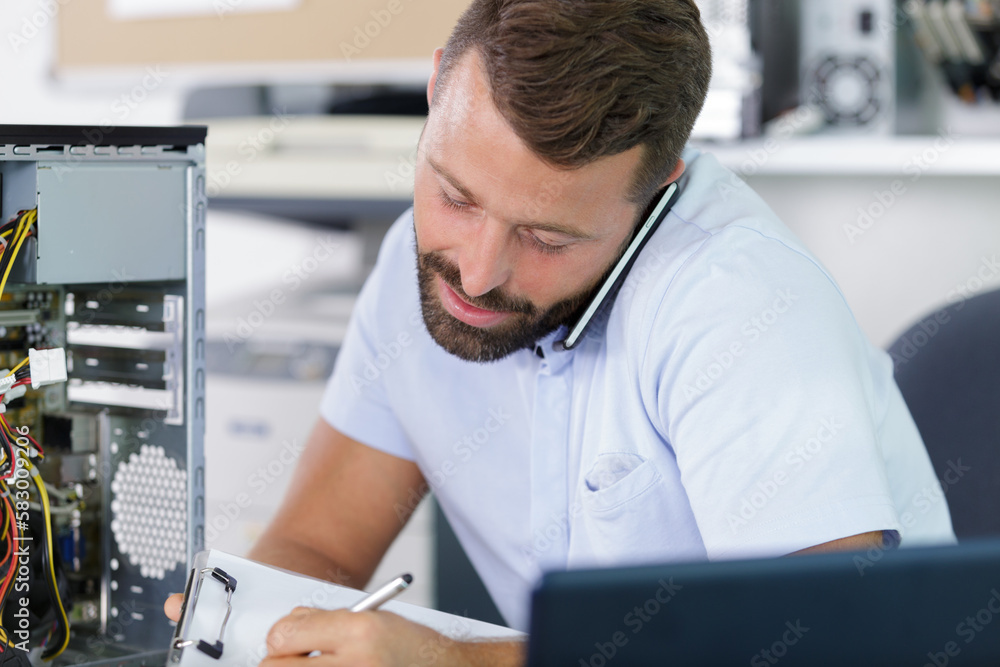 computer engineer on the phone repairing broken desktop computer engineer on the phone repairing broken desktop