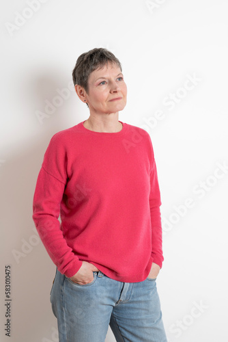 Paris, France - 03 18 2023: Studio shot of a mature woman with short hair posing and wearing a pink sweater photo