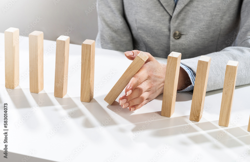 Business woman hand block domino effect Business woman hand block domino effect