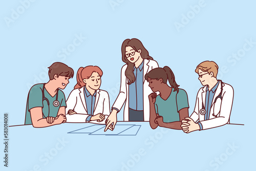Clinic staff meeting, with doctors sitting at table and head physician giving instructions to medical workers. Men and women working in clinic choosing tactics for treatment of patient