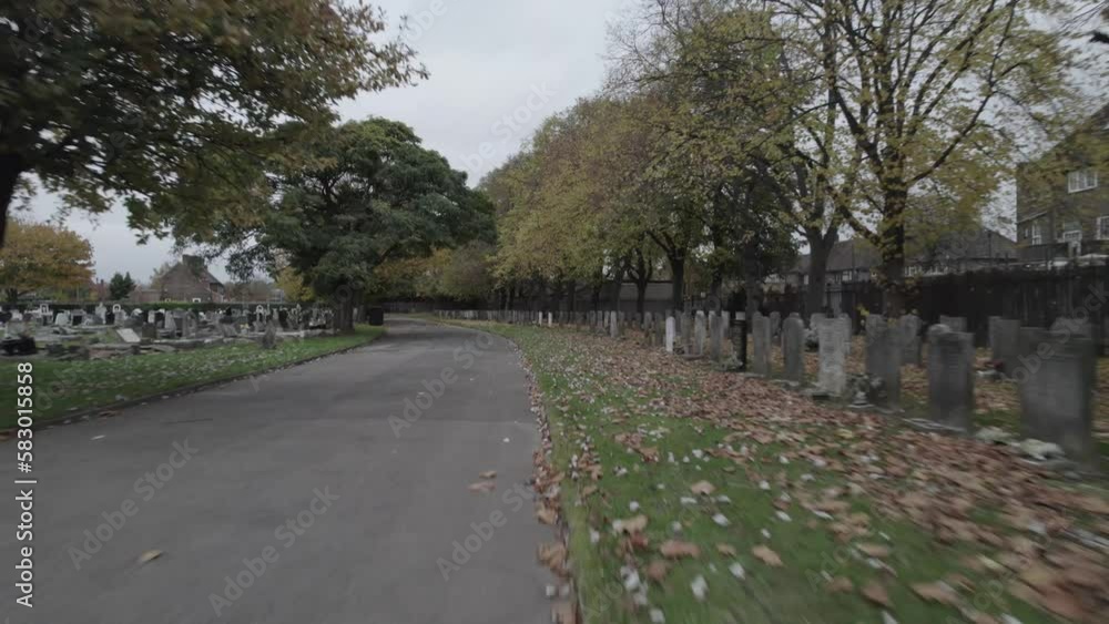Autumn cloudy day on town cemetery. Colourful leaves on grass. Rows of tombstones in sections. London, UK Autumn cloudy day on town cemetery. Colourful leaves on grass. Rows of tombstones in sections. London, UK