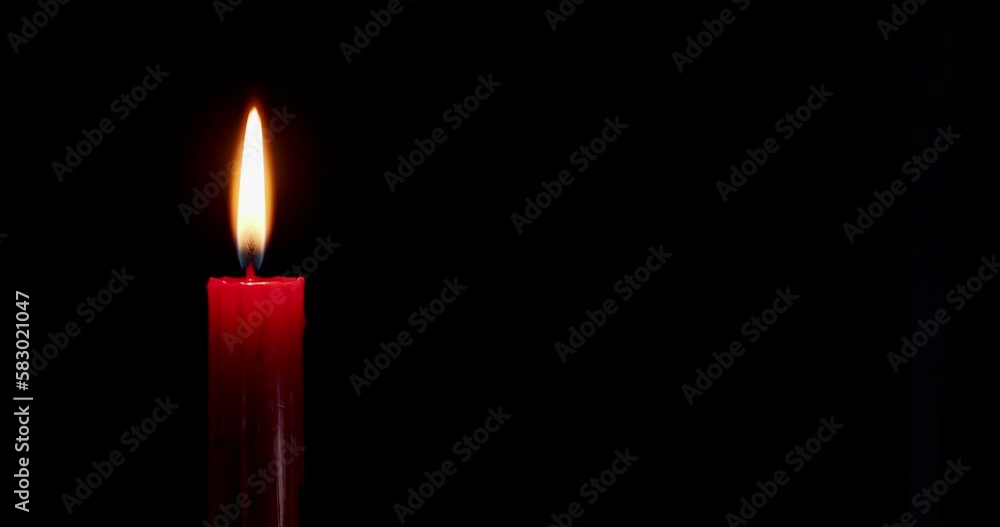 A single red candle burning. Isolated candle burning with dark background. Red paraffin candle with yellow shades burns on a black background. slow motion A single red candle burning. Isolated candle burning with dark background. Red paraffin candle with yellow shades burns on a black background. slow motion