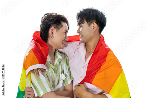 Portrait of cute Asian LGBT homosexual men or gay couple smiling and embracing, covered with pride rainbow flag, on white background. Looking at each other.