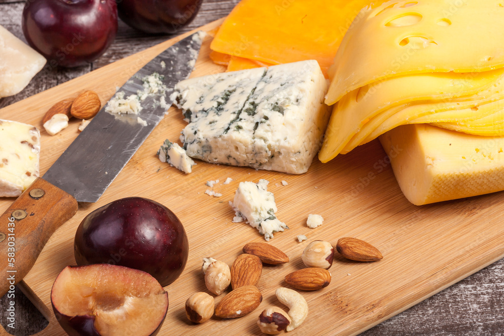 Healthy food. Cheese, nuts and fruits on wooden background. Gourmet delicatessen
