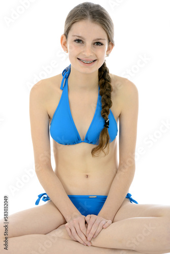 Cheerful teenage girl posing in blue bikini as swimwear or beach wear in studio isolated on white 