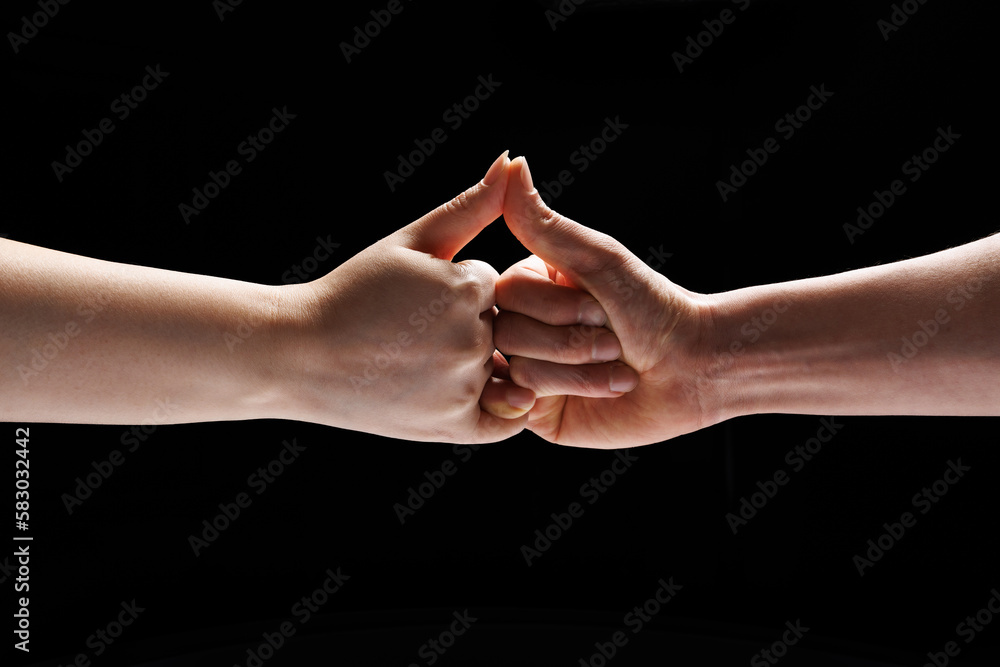 two people's hands made a gesture of promise on a black background