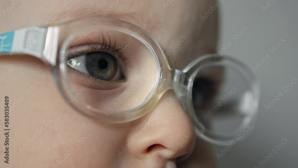 Closeup eye and pupil of infant with glasses. Caucasian baby with