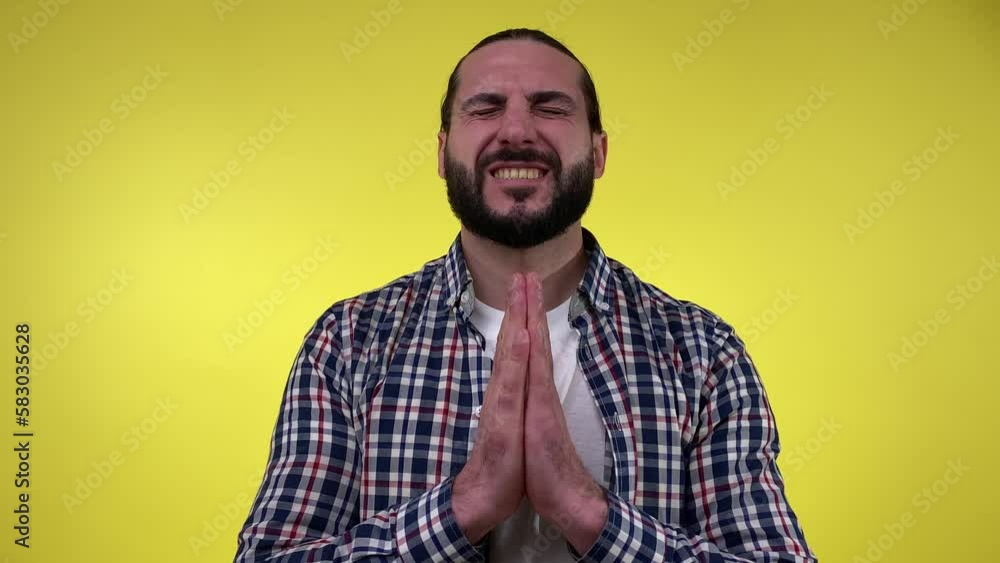 Portrait bearded man with closed eyes wishing good luck, holding hands together isolated on yellow background. Mid adult male person dreaming and waiting for all best. Fortune concept Portrait bearded man with closed eyes wishing good luck, holding hands together isolated on yellow background. Mid adult male person dreaming and waiting for all best. Fortune concept