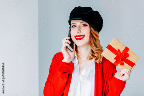 woman in red cardigan and hat with gift box