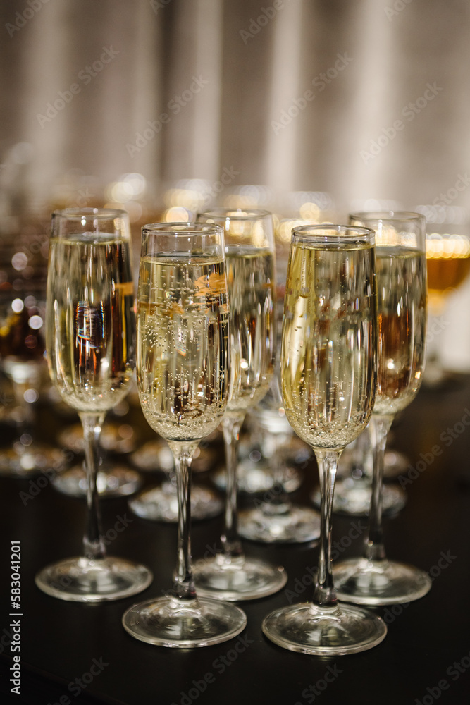Glasses of champagne on table, closeup. Many glass of white wine. Party time on holiday. Buffet. Selective focus. Celebration of birthday, baptism, wedding or corporate party. Catering service. Glasses of champagne on table, closeup. Many glass of white wine. Party time on holiday. Buffet. Selective focus. Celebration of birthday, baptism, wedding or corporate party. Catering service.