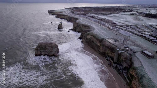 Drone climbs over rugged, winter coastline in North East England. Sunderland is in the background  photo