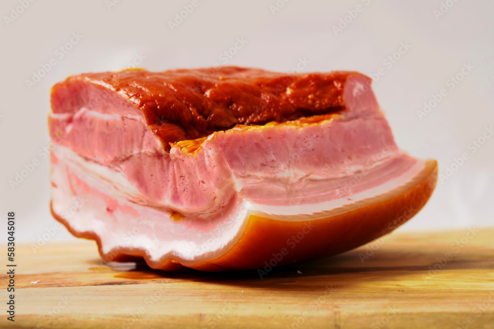 Traditional Polish smoked ham on a wooden board and light background. Ready to eat product made from pork meat. Classic and popular food in Poland and East European countries.