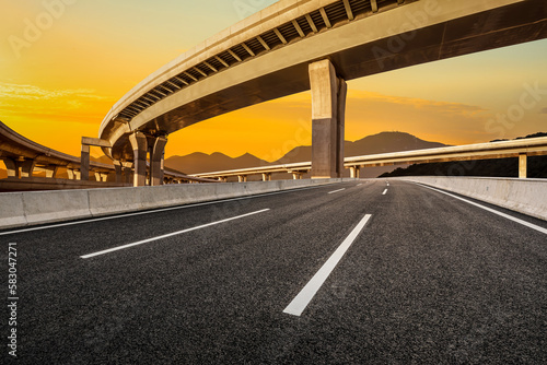 Asphalt road and bridge with mountain background at sunset © ABCDstock