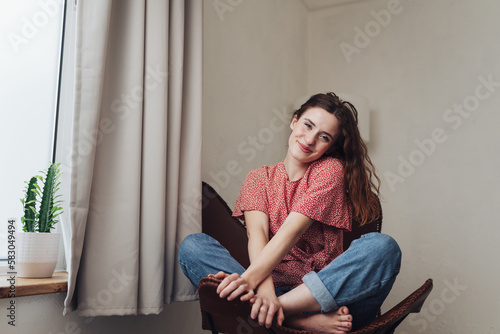 A woman relaxes in casual clothing during an indoor photo shoot, her long hair framing her emotion-filled face.