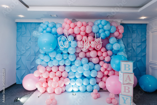 Photo zone, arch with pink and blue balloons, cubes for gender party. Boy or girl. Know gender of unborn child. Happiness of parenthood. Background, wall with text oh baby. Baby Shower party decor.