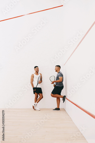 A time to play and a time to socialise. two young men chatting after playing a game of squash. © N F/peopleimages.com