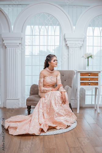 asian bride sitting on the chair and looking left with the windows at the background