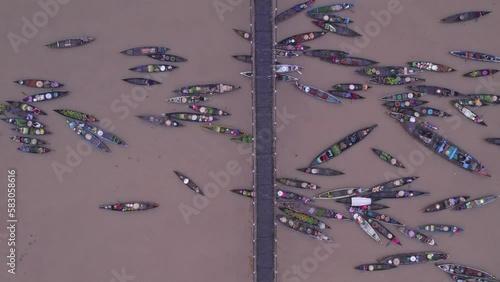 Traditional wooden boats with food floating on brown river in Indonesia under bridge photo