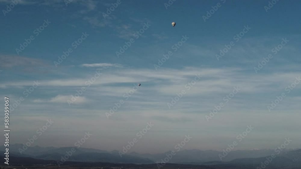 Aerial shot of two tiny air balloons under a light cloudy sky Aerial shot of two tiny air balloons under a light cloudy sky