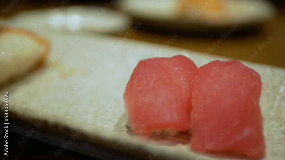 view to a plate of shushi while using chopstick to grab tuna shushi to eat in japanese restaurant, red tuna fish shushi for japanese meal dinner view to a plate of shushi while using chopstick to grab tuna shushi to eat in japanese restaurant, red tuna fish shushi for japanese meal dinner