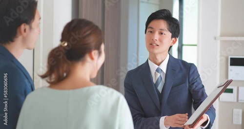 30代夫婦にモデルハウスを案内する不動産営業マンの若い男性