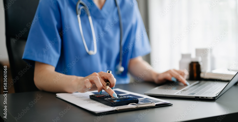 Fototapeta premium Healthcare costs and fees concept.Hand of smart doctor used a calculator and smartphone, tablet for medical costs at hospital in morning light