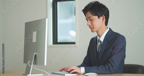 デスクワークをするスーツ姿の若い男性