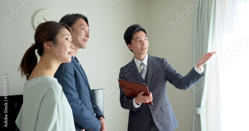 30代夫婦にモデルハウスを案内する不動産営業マンの若い男性