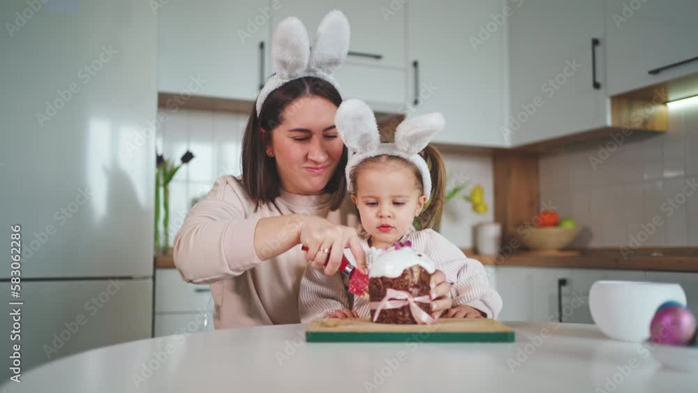 Beautiful mother and daughter are cutting a delicious Easter cake. Happy Easter. Beautiful mother and daughter are cutting a delicious Easter cake. Happy Easter.
