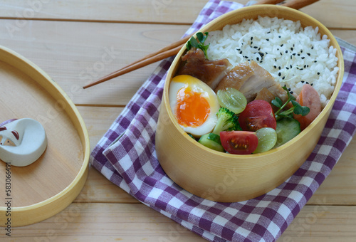 a delicious looking lunchbox consisting of steamed rice, boiled egg, grapes, and tomatoes