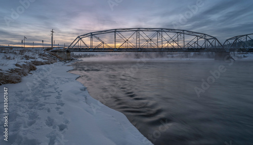 Winter sunrise on the Bow River and a bridge in Cochrane, Alberta, Canada
