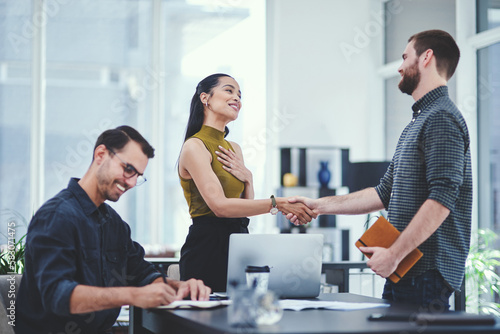 Im so honoured to be working with you. two young designers shaking hands during a meeting in an office.