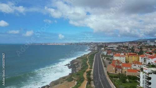 Flying backwards over cyclists and cars on Estoril Marginal, with an amazing view from the ocean.Portugal