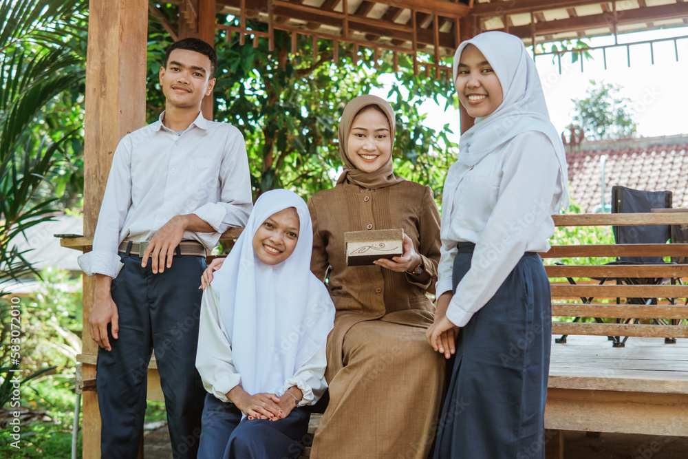 students smiling at the camera with a female teacher while holding handicrafts during an outdoor class