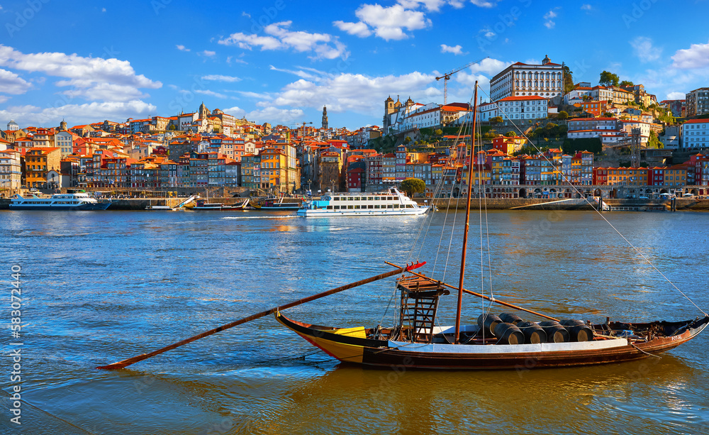 Old town of Porto, Portugal. Sunny day over silhouettes skyline roofs houses along river. Antique boat with port wine barrels on the water Douro River