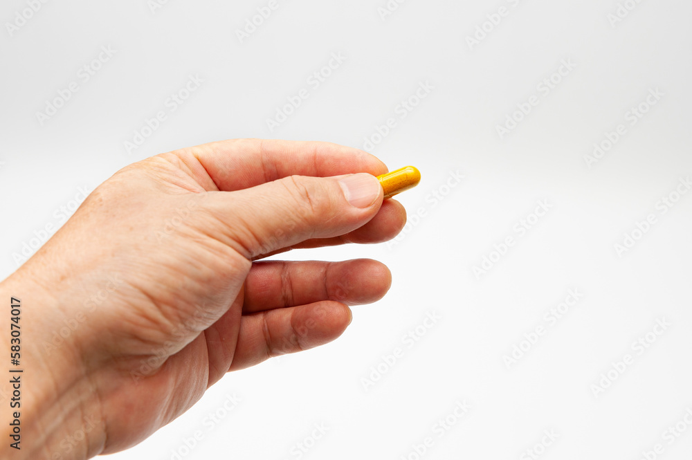 Man hand holding Turmeric supplement capsule isolated on white background with copy space Man hand holding Turmeric supplement capsule isolated on white background with copy space