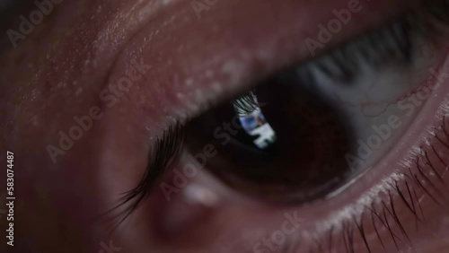 Detail of a man's eye looking at his smartphone screen while scrolling through online news and information. Online information and fake news, closeup macro detail of an eye. Scrolling smartphone feed