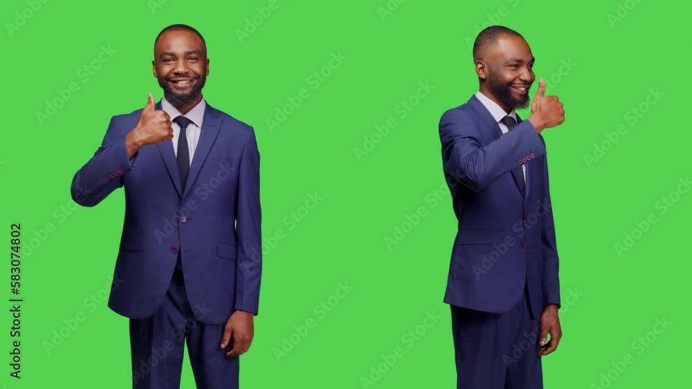 Male employee showing thumbs up sign on camera and expressing approval over greenscreen backdrop. Young man in suit giving like and doing agreement gesture in studio, copy space. Male employee showing thumbs up sign on camera and expressing approval over greenscreen backdrop. Young man in suit giving like and doing agreement gesture in studio, copy space.