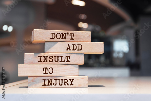 Wooden blocks with words 'Don't add insult to injury'. photo