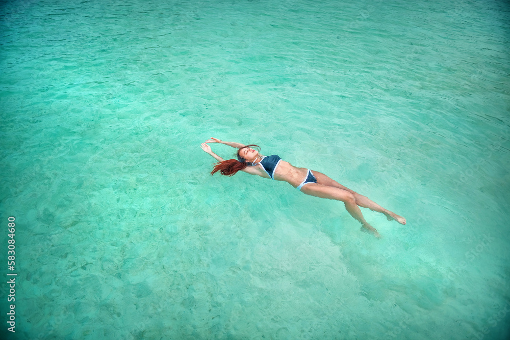 A beautiful young girl swims in the blue ocean. Girl in swimsuit. Holidays. On a rest. Beautiful planet.