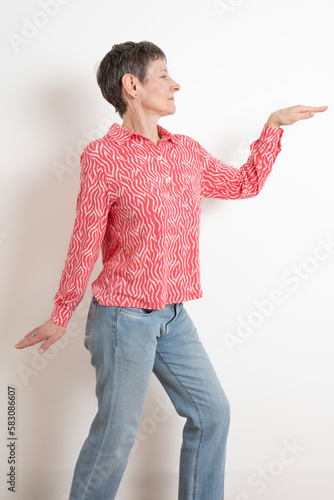 Paris, France - 03 18 2023: Studio shot of a mature woman with short hair posing and wearing a pink and white shirt photo