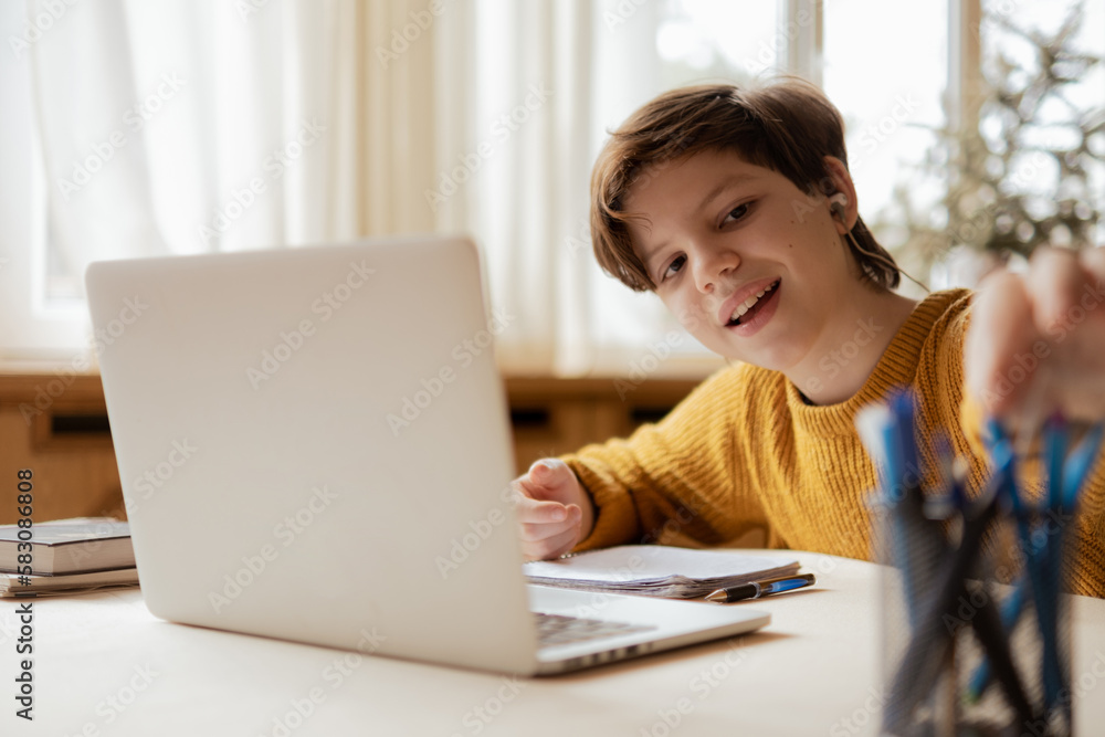 A joyful child learning at home in an online school. Choosing a pen to do an assignment