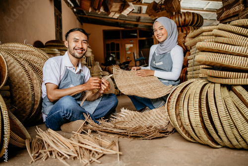 portrait of two handicraft worker is weaving traditional bamboo products in his workshop