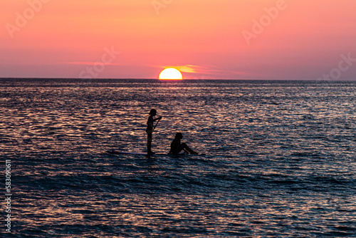 Fototapeta Naklejka Na Ścianę i Meble -  silhouette of  two girls paddling in the sunset