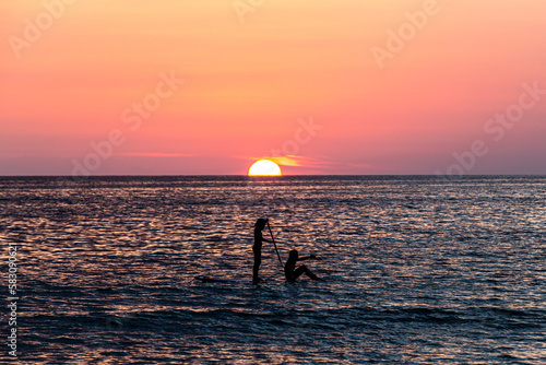 silhouette of two girls on SUP in the sunset