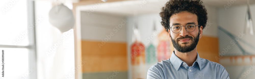Portrait of smiling businessman standing in modern office on colleagues background Portrait of smiling businessman standing in modern office on colleagues background