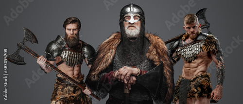 Portrait of antique vikings warriors with axes dressed in armor and fur.